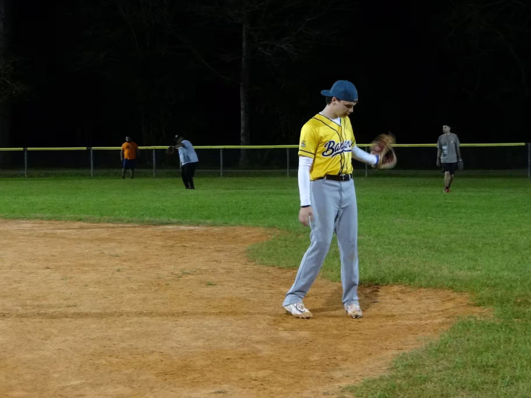 One of the members in their yellow Bananas jersey swinging his glove.